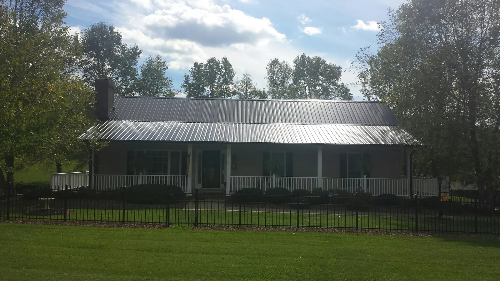 Gray metal roof on a brick ranch with a full width front porch — Gutter Guard Installation work by our crew in Beallsville