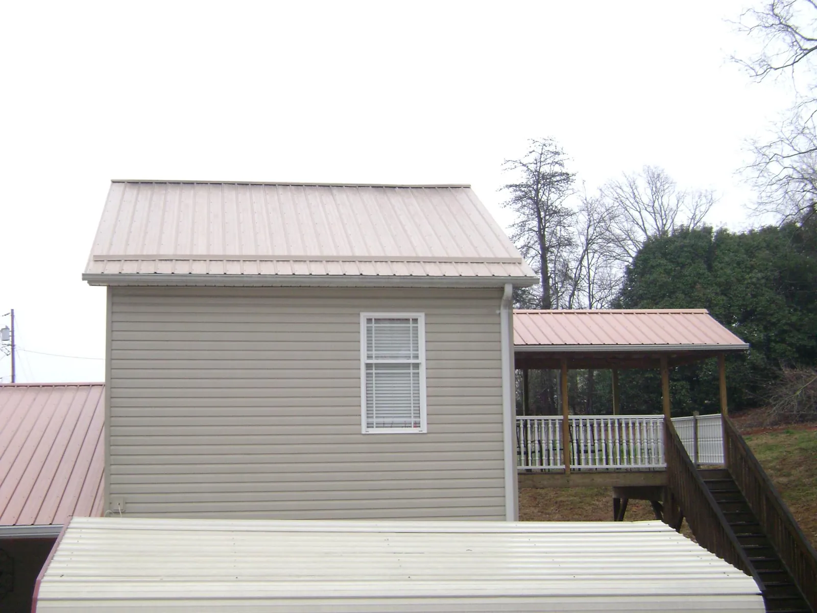 Tan metal roofs on a two story addition and attached porch, from a Roof Replacement job in Beallsville