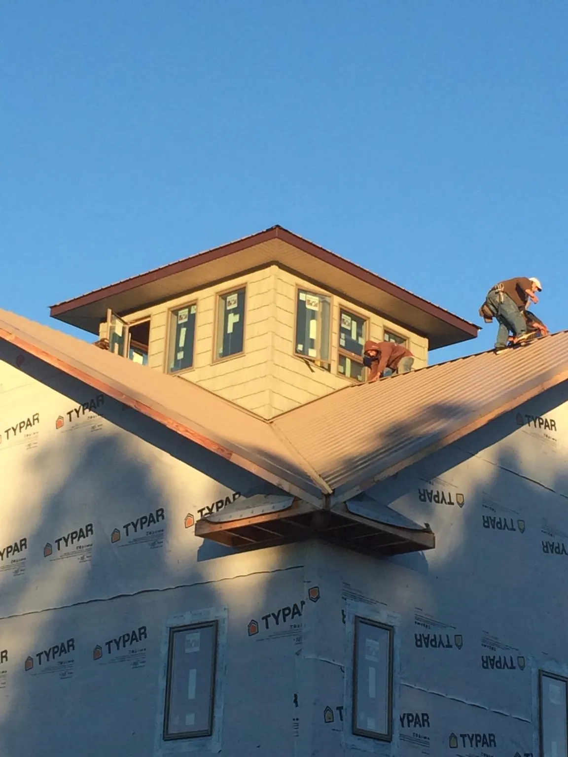Roofers working around a rooftop cupola on a new metal roof at sunset — Roof Waterproofing in Beallsville by Roofing Brothers